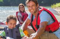 young family smiles while playing on kayaks