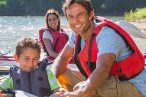 young family smiles while playing on kayaks