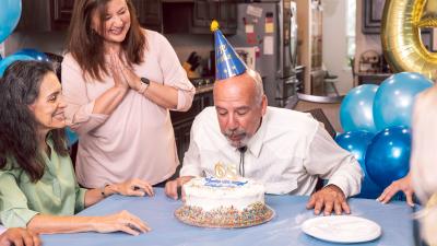 man blows out candles on his birthday cake with friends