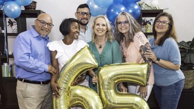 friends celebrate a 65th birthday with gold balloons