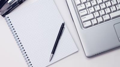 spiral notebook and pen next to laptop keyboard