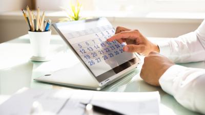 man's hand taps on desktop tablet with calendar