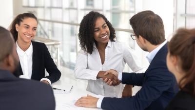 two professionals shake hands at a business meeting