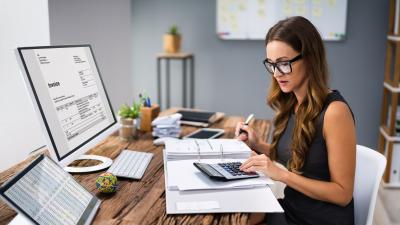 woman uses calculator for paperwork on desk