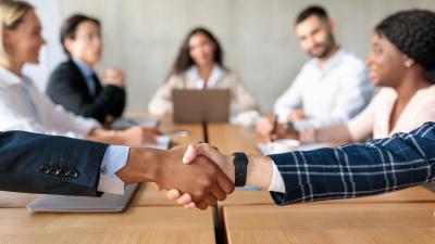 two professionals shake hands across a meeting table