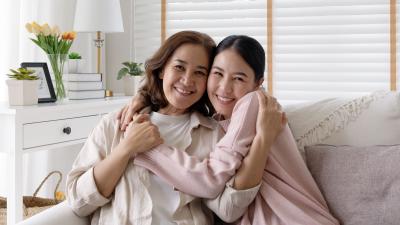mother and daughter hug while seated on sofa