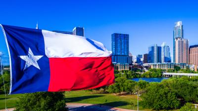 Large Texas flag waving in front of Austin skyline