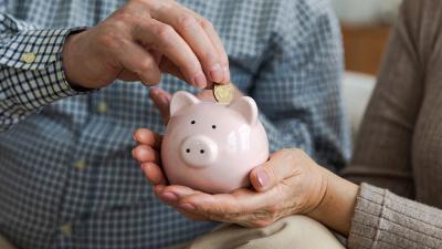 hand adds coins to a small piggy bank