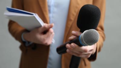 reporter holds two microphones and a notepad