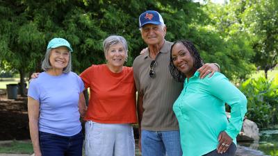 three women and one man smile while enjoying a park