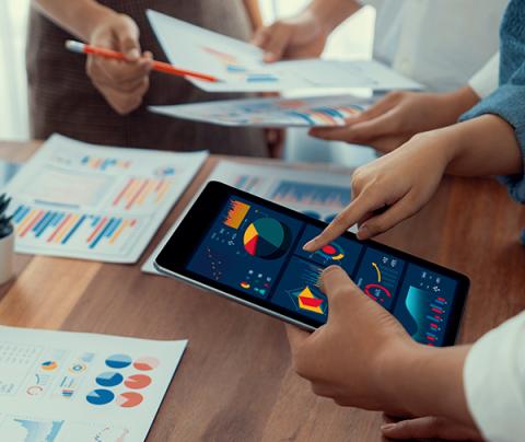 hand holds tablet with many charts and tables