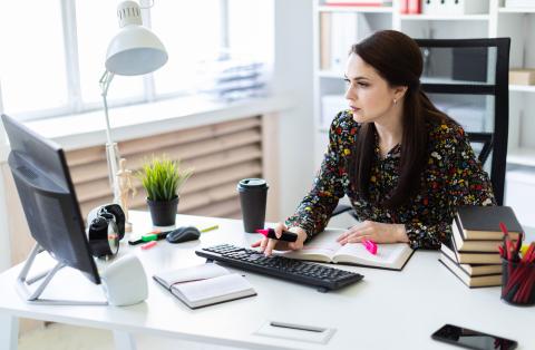 young professional looks at monitor while seated at bright desk