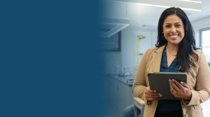 teacher in classroom holding a tablet