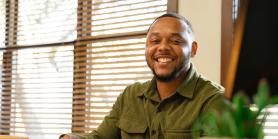 male teacher smiles while looking up from papers on desk