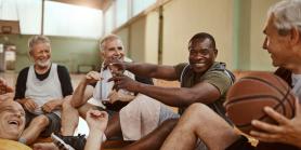 group of men in a gym laughing after playing basketball