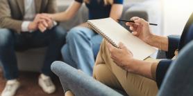 couple holds hands on a sofa during counseling session
