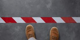 overhead view of two shoes stepping up to a red striped line on the groun