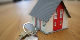 Mini model house resting beside key ring