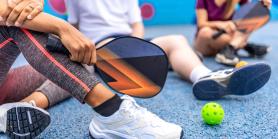 close-up of pickleball paddle and sneakers
