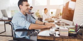 man sits in wheelchair while working at desk