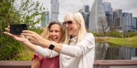 two female friends take a selfie in front of Austin skyline