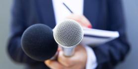 reporter holds microphone and small tablet