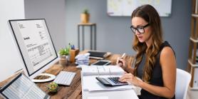 woman uses calculator for paperwork on desk
