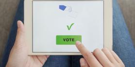hands hold tablet that shows a check mark and the word vote