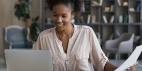 woman smiles as she looks at her laptop computer