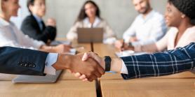two professionals shake hands across a meeting table