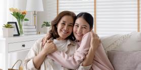 mother and daughter hug while seated on sofa