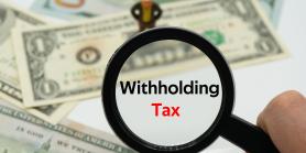 magnifying glass hovers over money for withholding tax