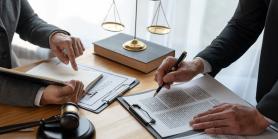 law scales and gavel on desk with two people meeting