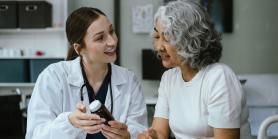 patient and doctor review a prescription while seated at table