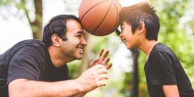 dad and son play with basketball outside