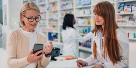 woman talks to pharmacist while looking at phone
