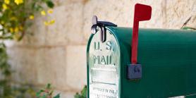 green mailbox with red flag in front of brick home
