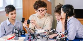 female teacher and three students build robotics project