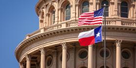 American flag and Texas flags waving in front of Texas capitol