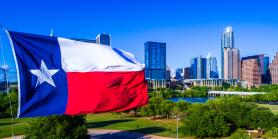 Large Texas flag waving in front of Austin skyline