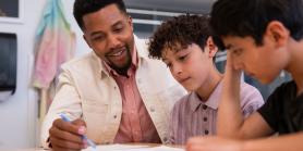 teacher works with two students on a paper