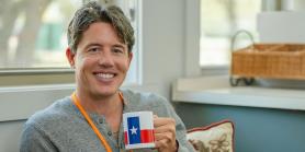 male teacher holds Texas flag coffee mug