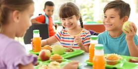 three children eat school lunch on trays