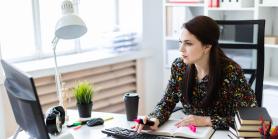 young professional looks at monitor while seated at bright desk