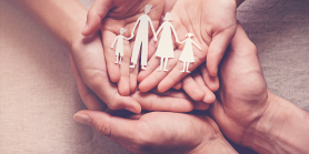 hands holding paper cutouts of family