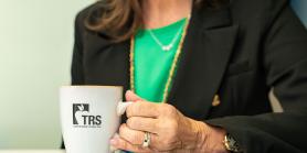 TRS staff member attends a meeting while holding a TRS coffee mug
