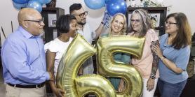 friends celebrating a 65th birthday with gold balloons