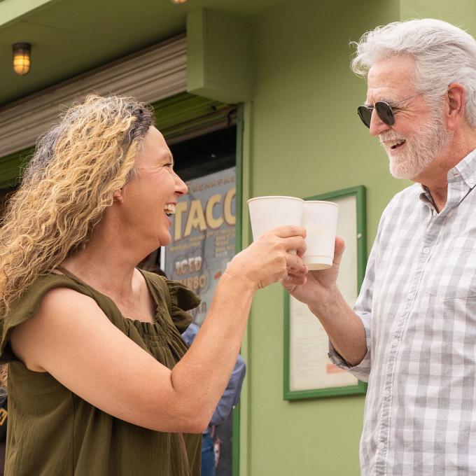 couple drinks coffee in paper cups at outdoor cafe