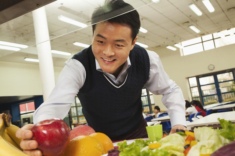 Man in grocery store picking apples