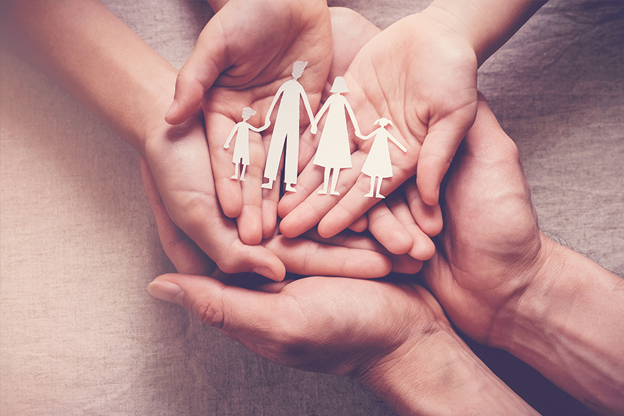 hands holding paper cutouts of family